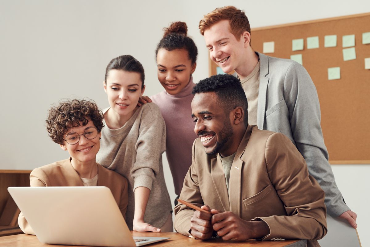 A professional team collaborating around a laptop